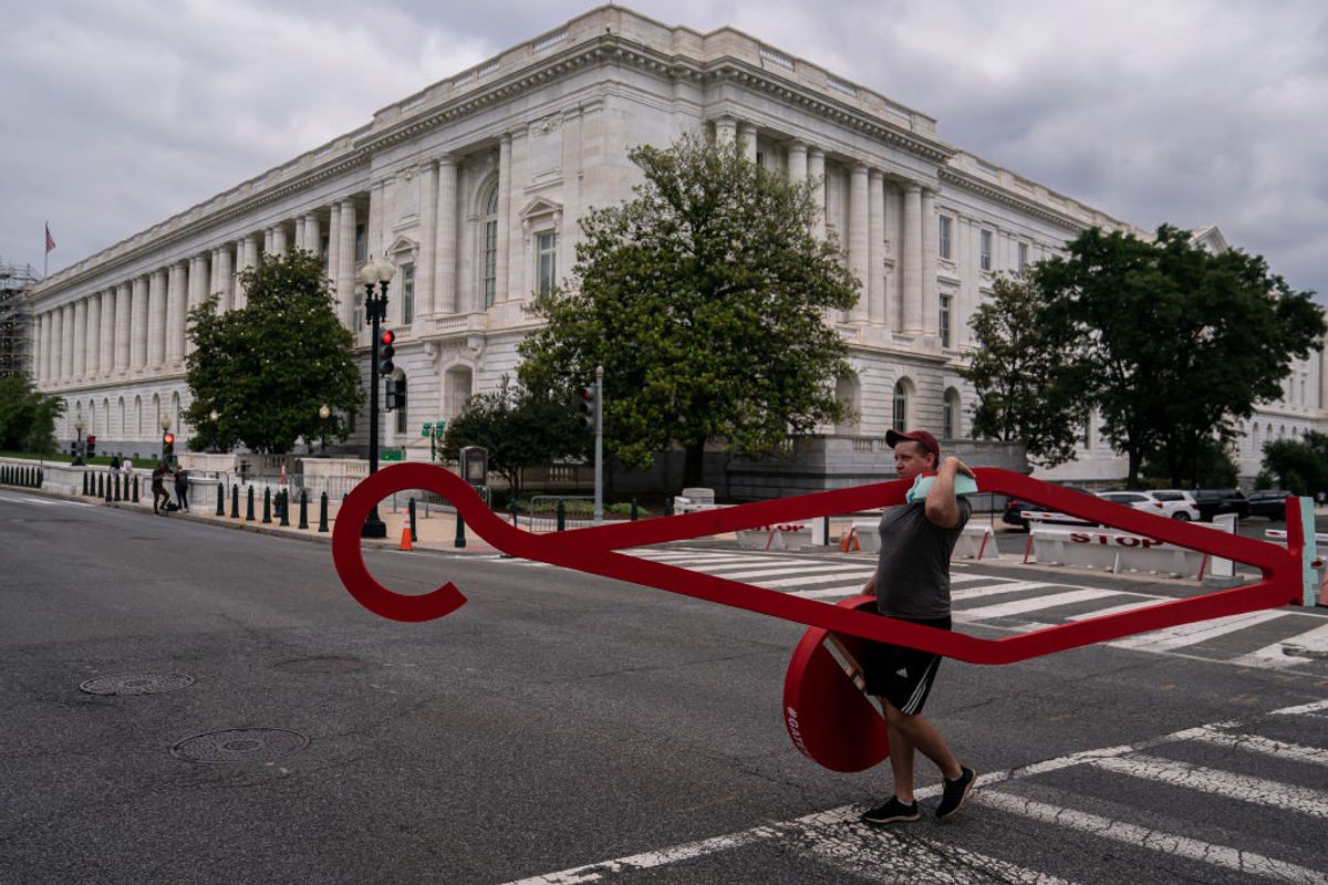 WASHINGTON, DC - JUNE 24: An abortion-rights activist walks toward the Supreme Court while carrying a large clothes hanger after the 6-3 ruling in Dobbs v. Jackson Womens Health Organization which overturns the landmark abortion Roe v. Wade case on June 24, 2022 in Washington, DC. The court eliminated the constitutional right to an abortion after almost 50 years. (Photo by Nathan Howard/Getty Images) (Getty Images)