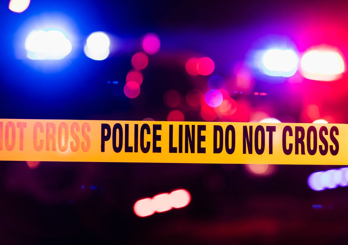 Accident or crime scene cordon tape, police line do not cross. It is nighttime, emergency lights of police cars flashing blue, red and white in the background (Cali9/Getty Images (Stock Photo))