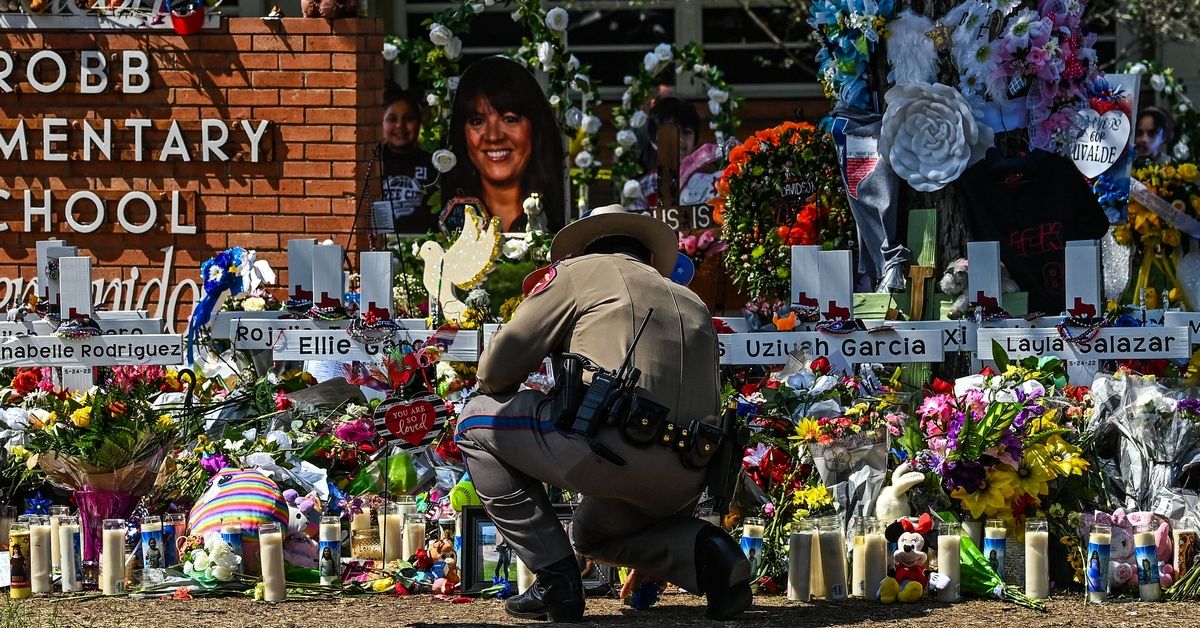 A police officer clears the makeshift memorial before the visit of US President Joe Biden at Robb Elementary School in Uvalde, Texas, on May 29, 2022. - The President and First Lady are in Uvalde to pay their respects following a school shooting. (Photo by CHANDAN KHANNA / AFP) (Photo by CHANDAN KHANNA/AFP via Getty Images) (Getty Images)