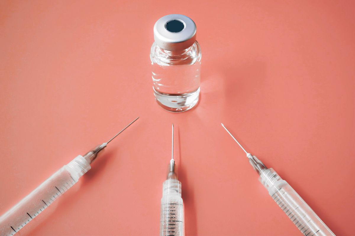 Close-up of syringes with needles and medical vial filled with liquid on orange background (Getty Images)