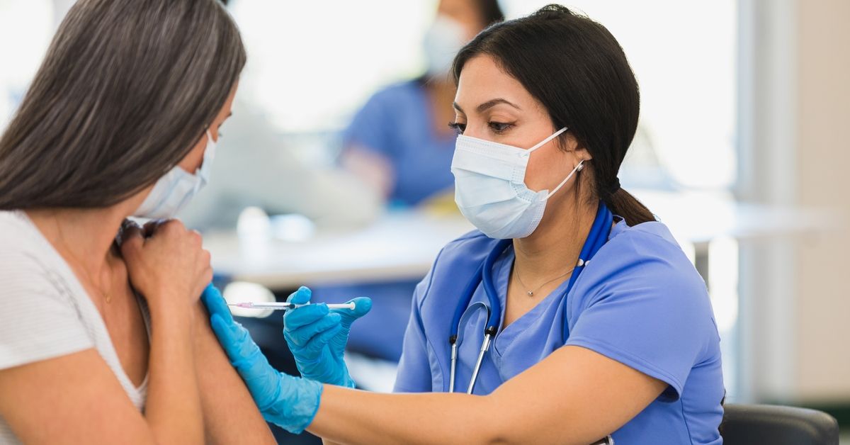 A close up photo of a mid adult female nurse giving a vaccine to an unrecognizable mid adult woman at a vaccination center. (Getty Images/Stock photo)