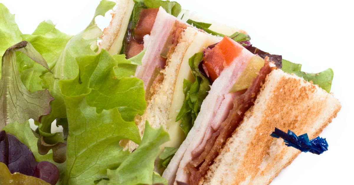 Club sandwich made with turkey, swiss cheese, bacon, lettuce and tomatoes on white background (Getty Images/Stock photo)