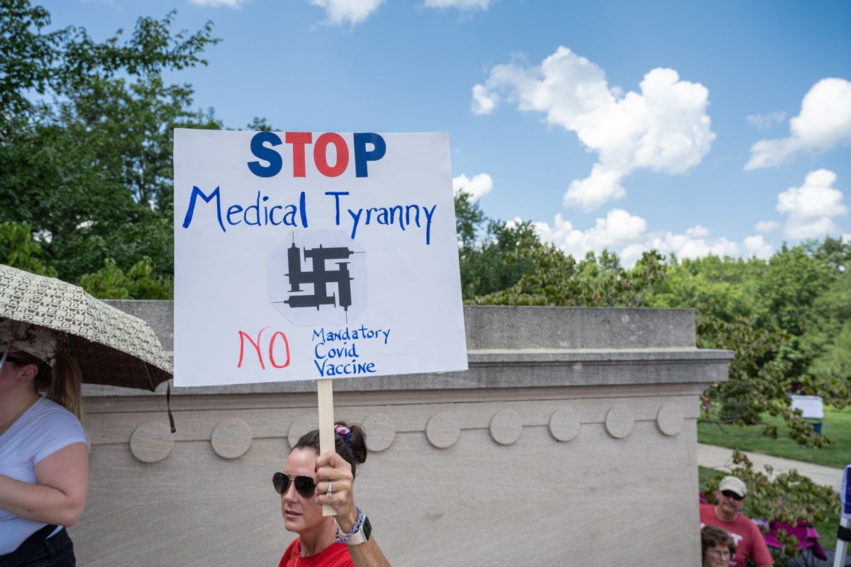 FRANKFORT, KY - AUGUST 28: A woman holds a sign denouncing COVID-19 vaccine mandates, illustrating syringes in the shape of a swastika, during the Kentucky Freedom Rally at the capitol building on August 28, 2021 in Frankfort, Kentucky. Demonstrators gathered on the grounds of the capitol to speak out against a litany of issues, including Kentucky Gov. Andy Beshears management of the coronavirus pandemic, abortion laws, and the teaching of critical race theory. Demonstrators and speakers also refuted the legitimacy of the 2020 United State presidential election, claiming that former President Donald Trump won and should be reinstated. (Photo by Jon Cherry/Getty Images) (Getty Images)