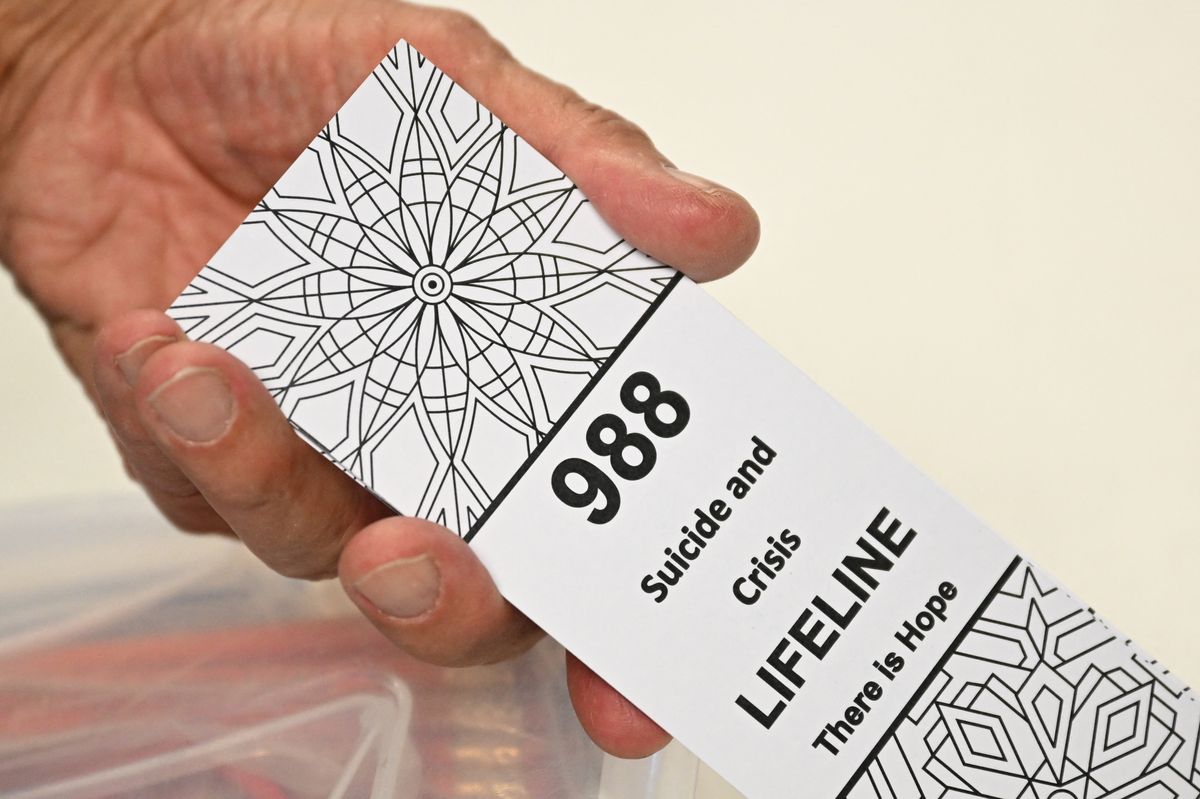 A bookmark for children with the 988 suicide and crisis lifeline emergency telephone number is displayed by Lance Neiberger, a volunteer with the Natrona County Suicide Prevention Task Force, while they speak about mental health and suicide awareness in Casper, Wyoming on August 14, 2022. - Sixteen years ago, after his son died by suicide, Lance Neiberger thought of taking his own life. 
Instead, the petroleum engineer -- who lives in central Wyoming -- is spearheading the difficult battle to curb the western US state's suicide rate, the highest in the nation. (Photo by Patrick T. FALLON / AFP) (Photo by PATRICK T. FALLON/AFP via Getty Images) (PATRICK T. FALLON/AFP via Getty Images)
