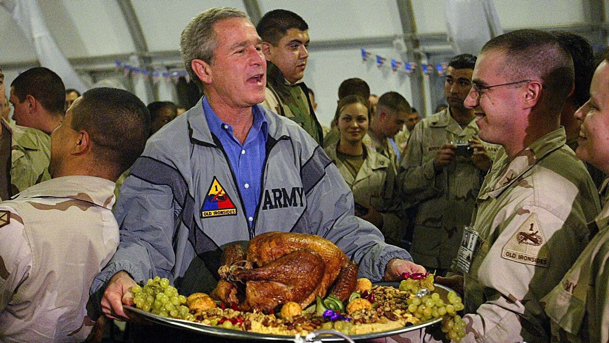 US President George W. Bush carries a platter of turkey and fixings as he visits US troops for Thanksgiving in Baghdad, 27 November, 2003.  (ANJA NIEDRINGHAUS/AFP via Getty Images)