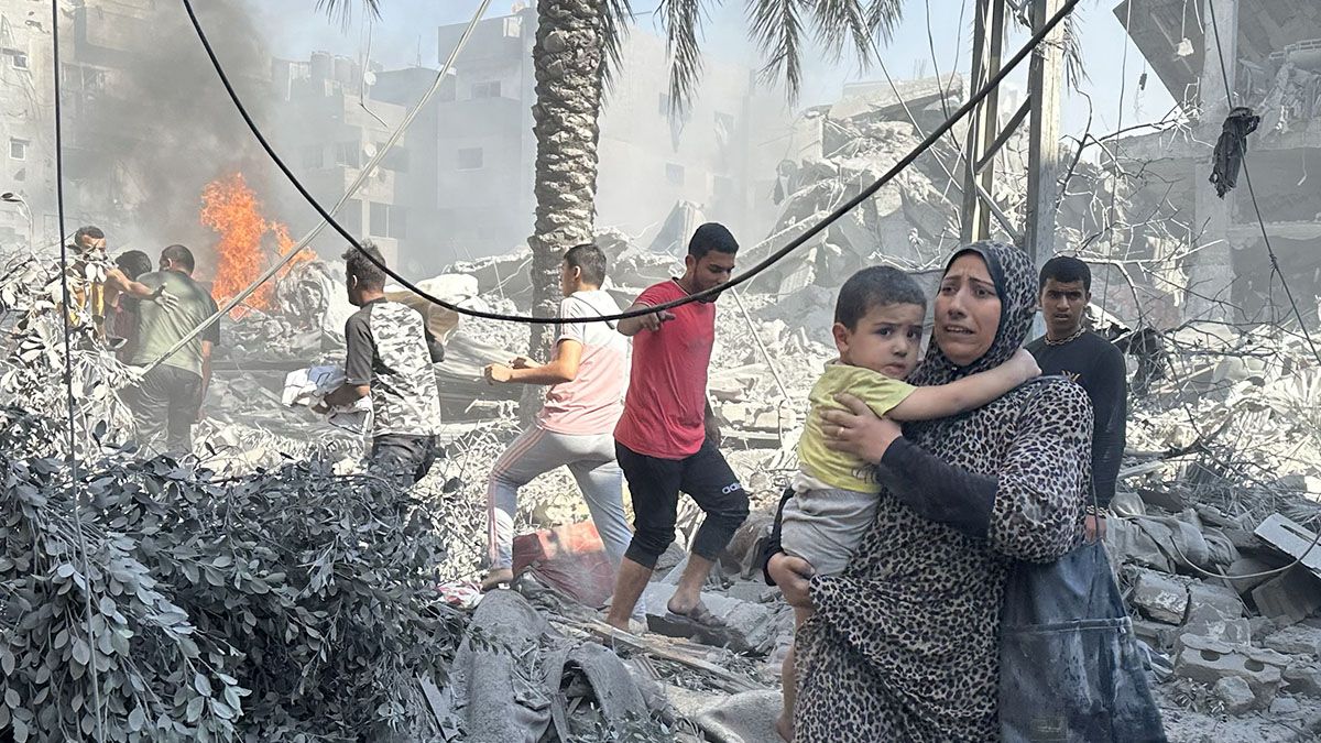 A Palestinian woman walks with a child on debris following the Israeli attacks on a building at Al Bureij Refugee Camp in Deir al-Balah, Gaza on Oct. 17, 2023. (Photo by Doaa Albaz/Anadolu via Getty Images) (Doaa Albaz/Anadolu via Getty Images)