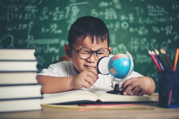 kid observing or studying educational globe model in the classroom. (Getty Images)