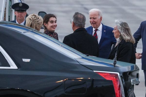 White people gather near a black car.