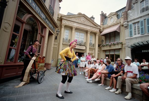 A person stands with their hands on their hips smiling at a group of people sitting down.